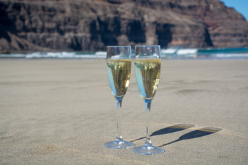 Two glasses of champagne or cava sparkling wine served on the white sandy tropical beach, luxury resort with sea view, romantic vacation