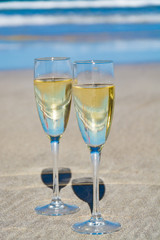 Two glasses of champagne or cava sparkling wine served on the white sandy tropical beach, luxury resort with sea view, romantic vacation