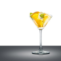 Mojito cocktail in martini glass with mint, orange and ice cubes on mirror table and place for inscription. Clipping path