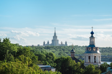 The buildings of Moscow city center with State University silhouette, some classical old church and colorful roofs. Beautiful city view of Moscow lush green nature, outdoor summer evening in Russia.