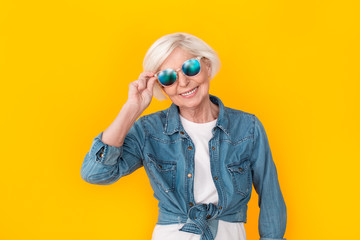 Fototapeta premium Senior woman traveler studio isolated on yellow wall wearing sunglasses