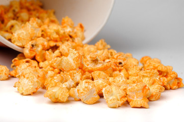 yellow spicy popcorn scattered from a bucket on a white background