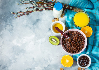 Healthy breakfast with bowl of cereal, orange juice, milk, jam and fruits on concrete background. Balanced diet.