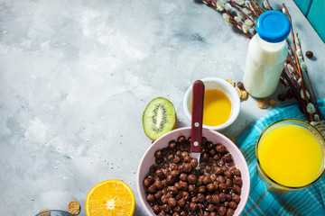 Healthy breakfast with bowl of cereal, orange juice, milk, jam and fruits on concrete background. Balanced diet.