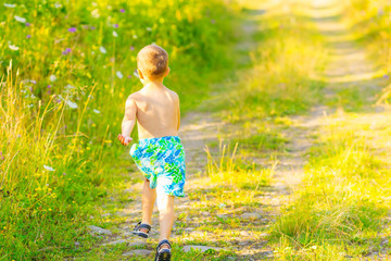 a little boy in shorts and sandals runs fast on a path