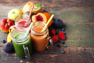 Sweet smoothie in glass jars with fruits on wooden table