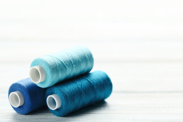 Colourful thread spools on white wooden table