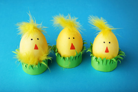 Yellow eggs with funny chicken faces on blue background