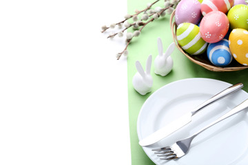 Kitchen cutlery with easter eggs and ceramic rabbits on white background