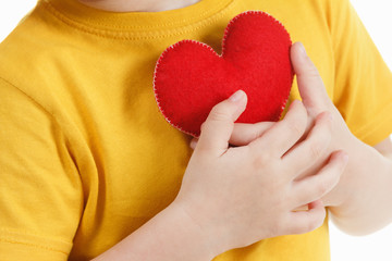 Smiling boy holding a red heart figurine. symbol of love, family, . Concept of the family and children.