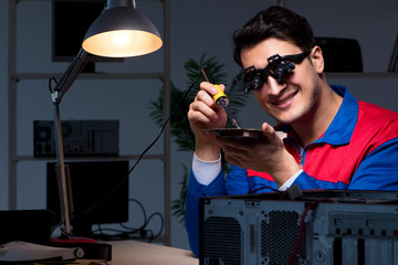 Computer specialist repairing PC late at night