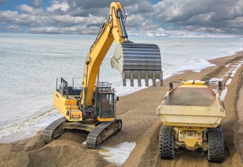 Construction - Heavy Machinery Construction Site - Engineering - Sea Defence. Large plant machinery being use to build the beach sea defence at Seaford, East Sussex, UK