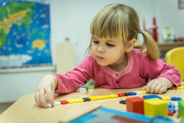 Curiously kid playin with puzzle toy in kindergarten