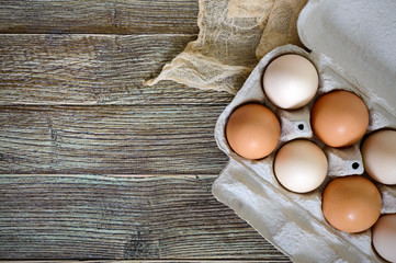Fresh raw chicken eggs in carton egg box on wooden background. The top view on brown and white eggs. Close-up view. The main ingredient for many dishes. Free space for inscriptions, notes.