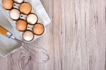 Fresh raw chicken eggs in carton egg box on wooden background. The top view on brown and white eggs. Close-up view. The main ingredient for many dishes. Free space for inscriptions, notes.