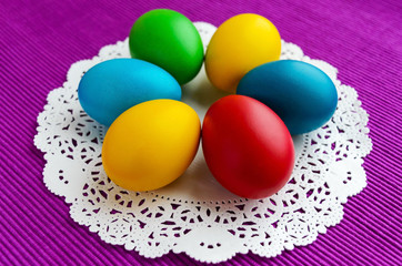 Fototapeta na wymiar Colorful eggs for holiday Easter on a white napkin on a vivid background.