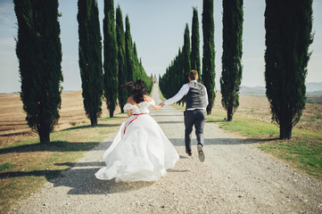 Happy stylish smiling couple walking and kissing in Tuscany, Ita