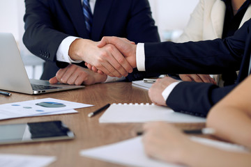 Close up of business people shaking hands at meeting or negotiation in the office. Partners are satisfied because signing contract