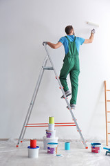 Male decorator painting wall with roller indoors © New Africa