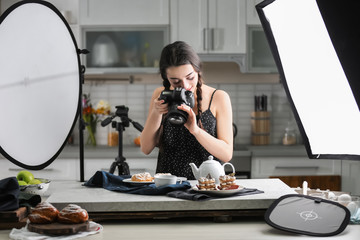 Young woman with professional camera taking food photo in studio