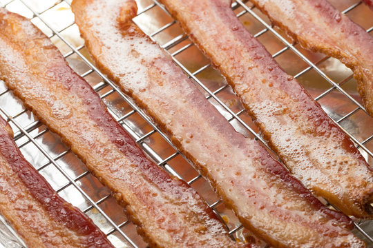 Macro close up on fried bacon strips with grease bubbles, on a wire baking sheet