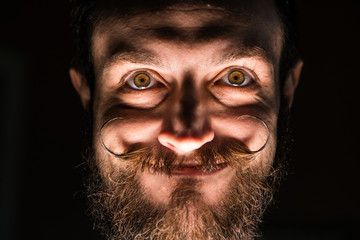 Inventor Hipster with Beard and Mustages in the Dark Room. Smiling Trickster.