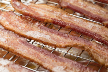 Macro close up on fried bacon strips on a metal cooling rack