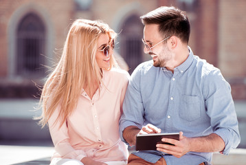 Happy couple with tablet sitting outdoor