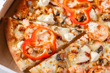 Pizza box delivery concept. Open box with hot tasty italian sliced pizza with salmon, eel, seafood, olives, basil, tomato, mushrooms.