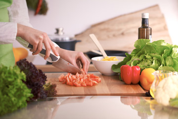 Close Up of human hands cooking vegetable salad in kitchen on the glass table with reflection. Healthy meal, and vegetarian food concept