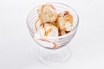 Vanilla ice cream with caramel syrup on white background. Scoops of vanilla ice cream in glasses bowl.
