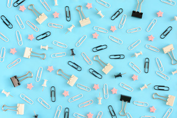 Stationery chaotically scattered on a turquoise background. White and black paper clips, clerical...