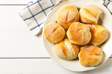 Bunch of whole, fresh baked wheat buns with wheat ears on white wooden table