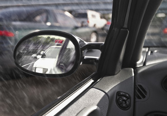 view of police car in side view sideview mirror while raining