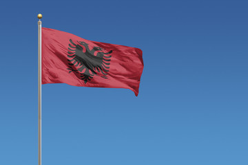 Fototapeta na wymiar Albanian flag in front of a clear blue sky