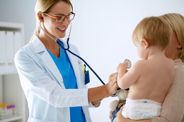 Female doctor is listening kid with a stethoscope in clinic