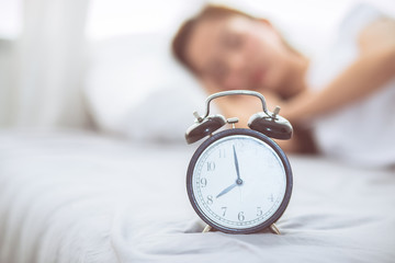 Beautiful asian young woman turn off alarm clock in good morning, wake up for sleep with closeup...