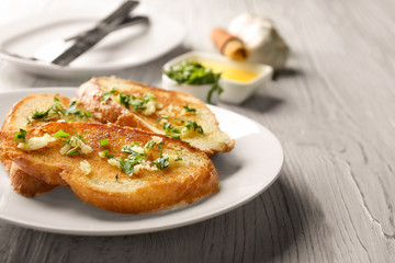 Plate with delicious homemade garlic bread on table