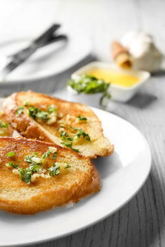Plate with delicious homemade garlic bread on table