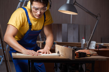Worker working in repair workshop in woodworking concept