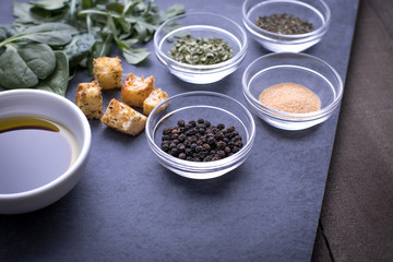 Glass ingredient dishes of peppercorns and spices on a slate