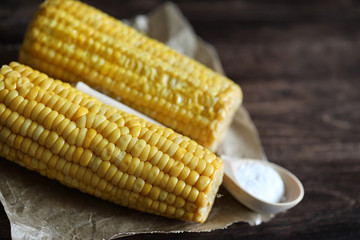 Boiled corn cob with salt on a wood