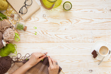 A woman knits a white and broun knitted fabric of woolen yarn. Knitting needles. Aged background....