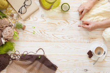 A woman knits a white and broun knitted fabric of woolen yarn. Knitting needles. Aged background....