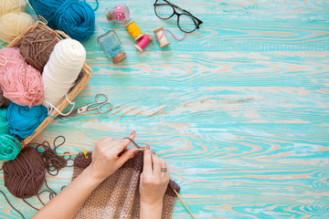 A woman knits a white and broun knitted fabric of woolen yarn. Knitting needles. Aged background....