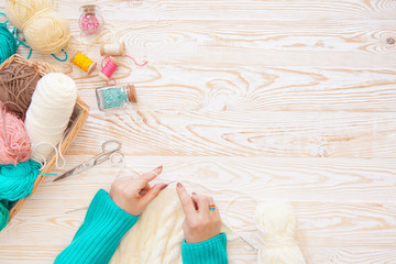 A woman knits a white and broun knitted fabric of woolen yarn. Knitting needles. Aged background....
