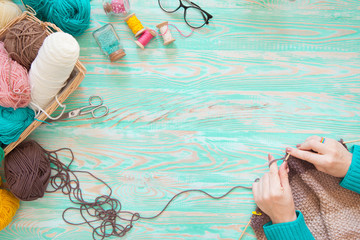 A woman knits a white and broun knitted fabric of woolen yarn. Knitting needles. Aged background....