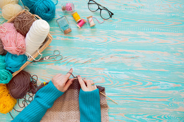 A woman knits a white and broun knitted fabric of woolen yarn. Knitting needles. Aged background....