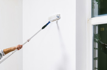 Painter working with paint roller and brushes to paint the room