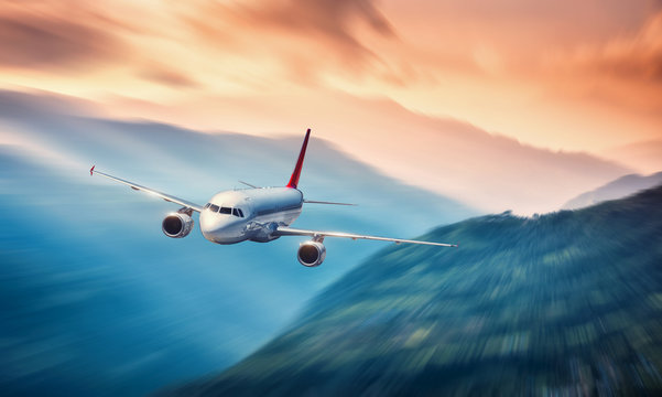 Airplane in motion. Aircraft with motion blur effect is flying over hills and mountains at sunset. Passenger airplane, blurred clouds. Passenger aircraft in motion. Business travel. Commercial.Concept © den-belitsky